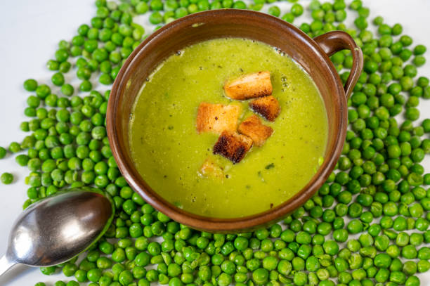 istock Pea soup with fried bread in bowl on background with many peas. 1355057220