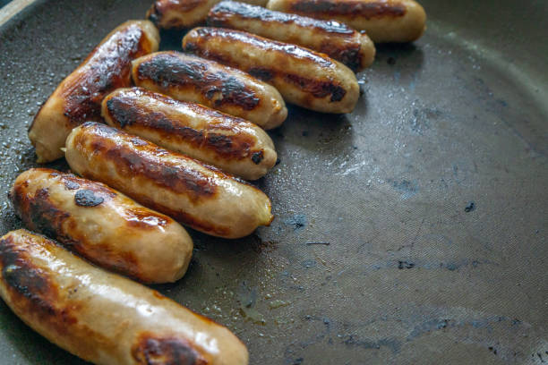 istock Pork sausages sizzling in a skillet 1355057618