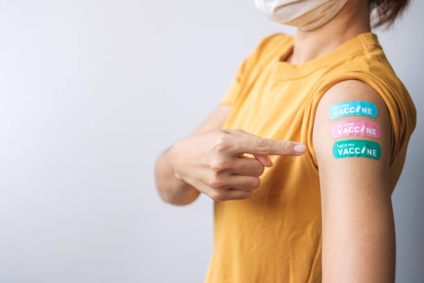 woman showing plaster after receiving covid 19 vaccine. vaccination, herd immunity, side effect, booster dose, vaccine passport and coronavirus pandemic - number 33 fotos imagens e fotografias de stock