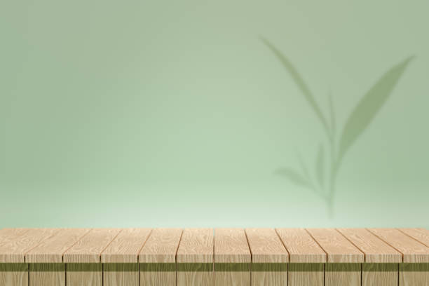 istock Cosmetic display product stand, Wood texture table desktop with pastel green wall and sunlight green tea leaf shadow background. 3D rendering illustration 1355059973