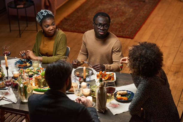 istock African couple sitting at dining table with friends 1355060651