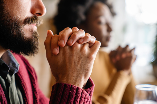 Joven pareja multiétnica orando al Señor para que bendiga su comida y su día photo