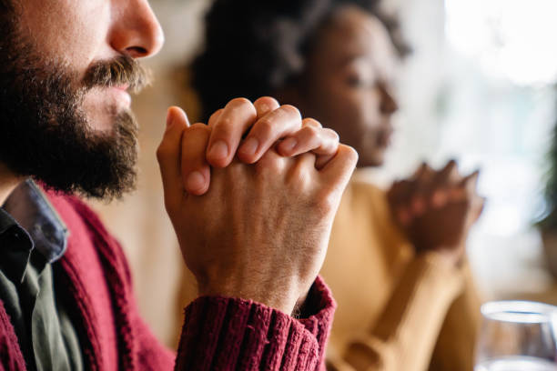 joven pareja multiétnica orando al señor para que bendiga su comida y su día - praying fotografías e imágenes de stock