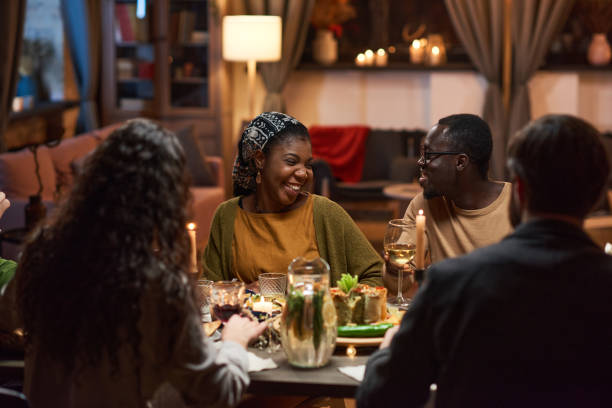 istock Happy friends sitting at dining table 1355060679