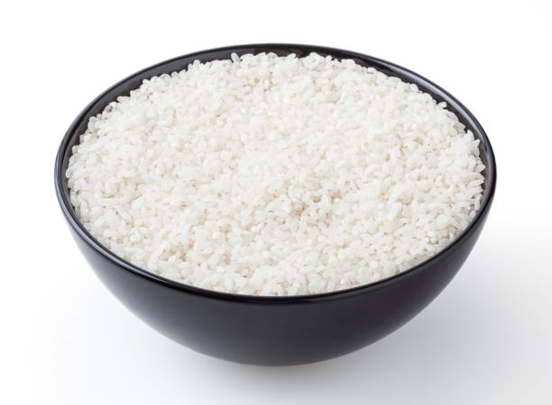 istock Uncooked round rice in black bowl isolated on white background with clipping path 1355060960