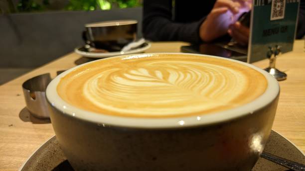 istock Coffee in brown cup on wooden table in cafe on lighting background 1355060977