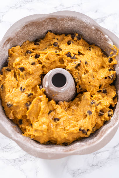 istock Pouring cake batter into a greased bunt cake pan to bake chocolate pumpkin bundt cake 1355062012