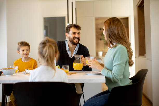 istock Young happy family talking while having breakfast at dining table 1355063247