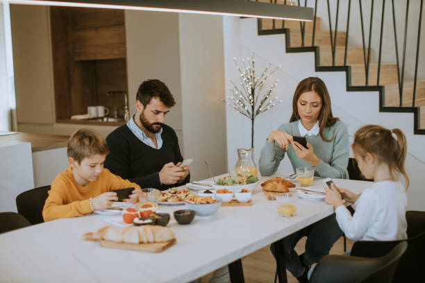 istock Family using mobile phones while having breakfast at dining table at apartment 1355063249