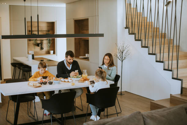 istock Family using mobile phones while having breakfast at dining table at apartment 1355063275