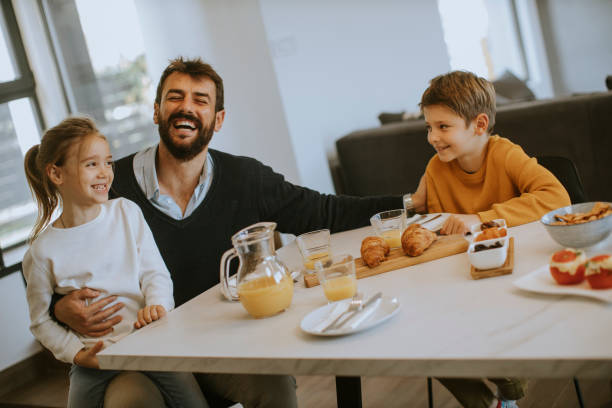 Father having breakfast with his son and daughter at home stock photo