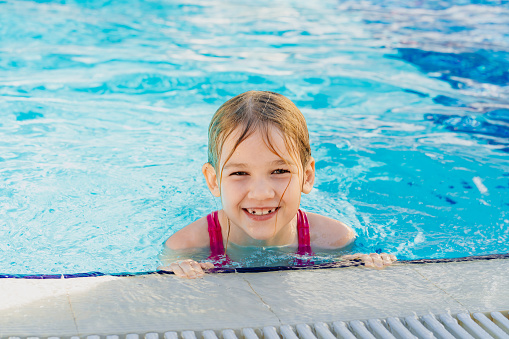 a funny little girl learns to swim without assistance at the side of the pool. safety of children on the water. inflatable toys for swimming and playing in the water. swimming training.