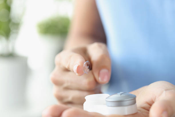 istock Woman finger pulling out contact lens from plastic container closeup 1355067343