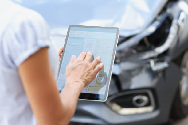 agent driver filling out insurance claim on digital tablet against background of broken car closeup - vehicle wreck imagens e fotografias de stock