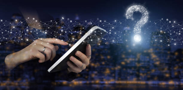 istock FAQ Concept image.Find answer online. Hand touch white tablet with digital hologram question mark sign on city dark blurred background. 1355068674
