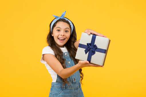 Definite must. black friday discount. summer shopping sales. best presents and gifts. little girl open box. surprised kid on yellow background. birthday surprise for her. bargain sale concept.