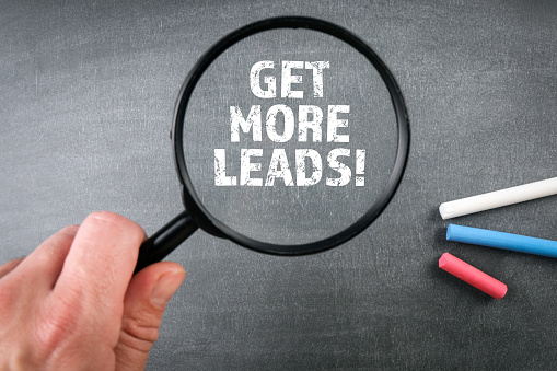 GET MORE LEADS. Magnifying glass on a dark chalkboard.