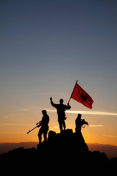 istock Three unrecognizable armed soldiers with the Albanian flag 1355070057