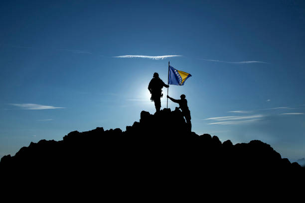 istock Two unrecognizable soldiers raise the Bosnuan flag 1355070075