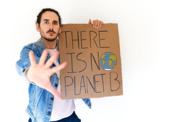 istock Medium shot of climate activist holding banner and making stop gesture 1355072140