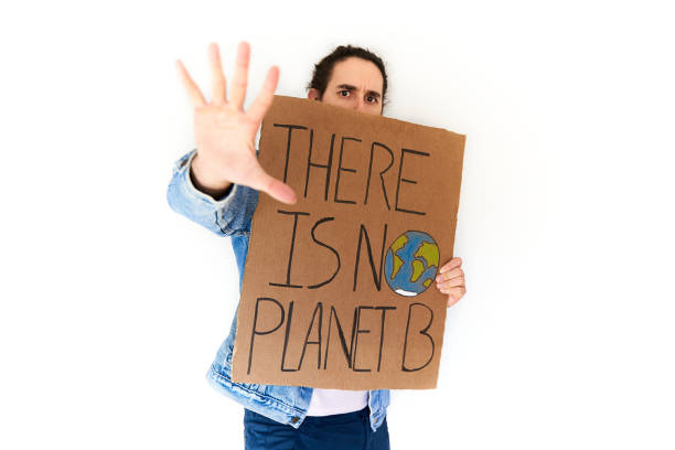 istock Fight climate change concept. Serious young man holding cardboard banner over white background waving hand 1355072294