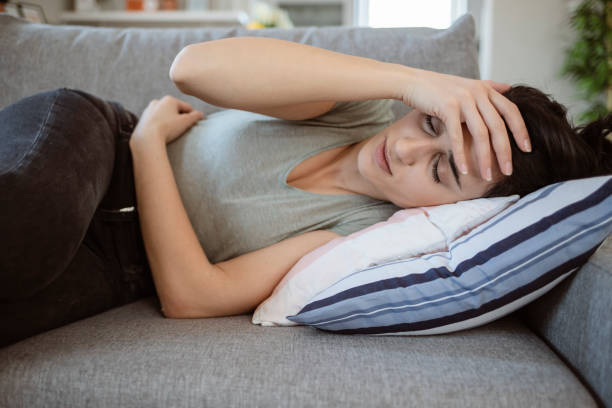 putus asa wanita muda berbaring di sofa menderita sakit kepala - stomach potret stok, foto, & gambar bebas royalti