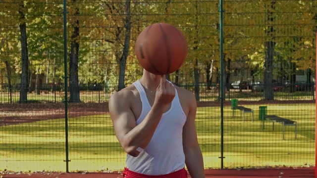 Man practicing to balance basketball ball on finger. Player spinning ball