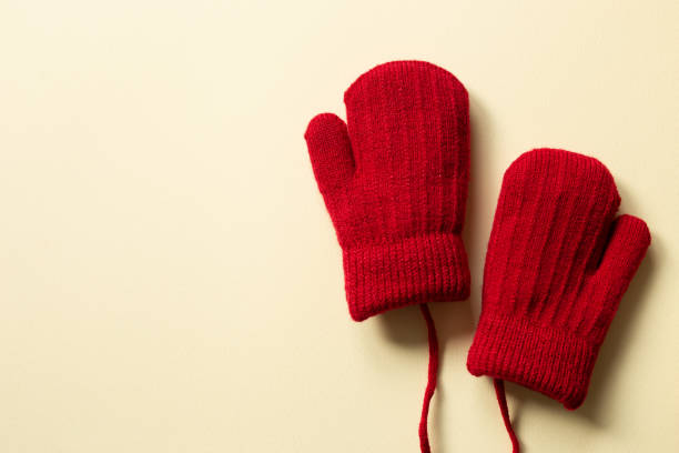 Winter red knitted gloves on beige background. top view, copy space