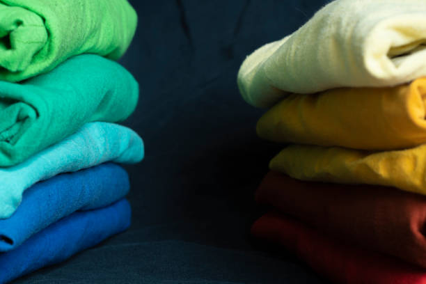 istock Stacks of multicolored fabrics in cool and warm colors are compared next to each other. Background with folded clothes with blank space for information. T-shirts of different colors 1355079621