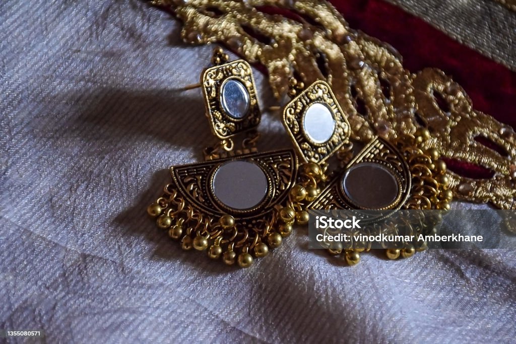 Stock photo of beautiful Indian jewelry golden mirror zumka or earring on white background. traditional Indian trendy jewelry, focus on object at Bangalore city Karnataka India. Stock photo of beautiful Indian jewelry golden mirror zumka or earring on white background.traditional Indian trendy jewelry, focus on object at Bangalore city Karnataka India. Antique Stock Photo