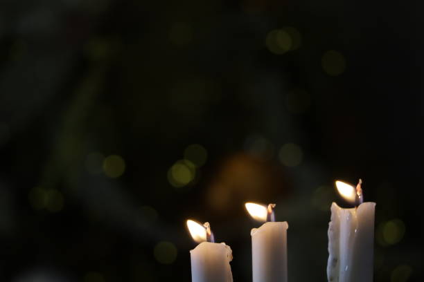 istock three candles burning in the dark on a blurred background 1355081887