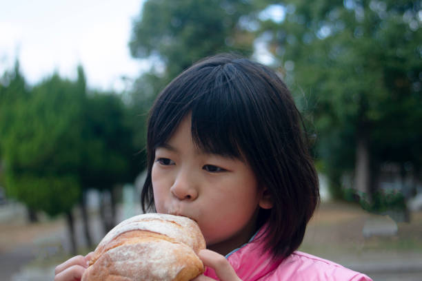 istock Girl having a large bread outdoors 1355082597