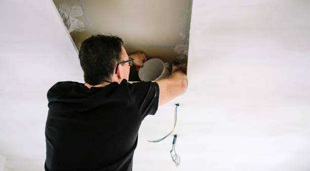 istock Man placing tube for kitchen hood installation on kitchen ceiling 1355083065