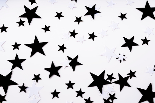 Confetti black and white stars on a white background. Top view