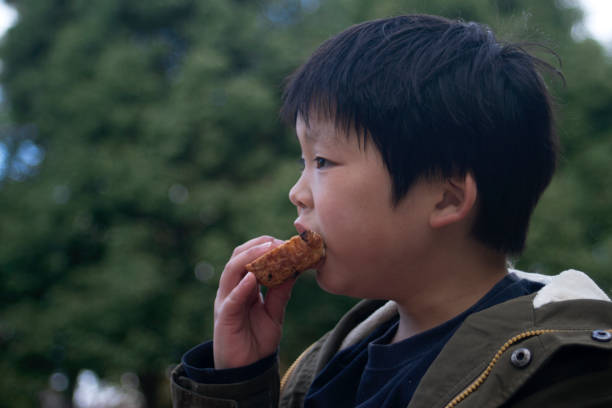 istock Boy eating a bread outdoors 1355083169