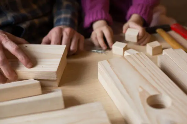 Photo of Making a wooden bird feeder. Dad and daughter are doing together. The concept of spending time together. Bird care