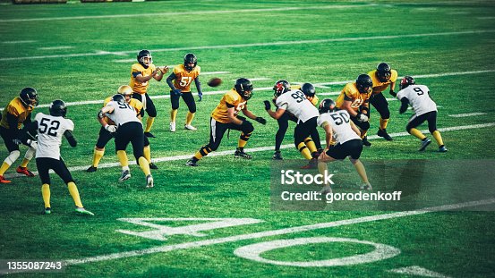 istock American Football Teams Start Game: Professional Players, Aggressive Face-off, Tackle, Pass, Fight for Ball and Score. Warrior Competition Full of Brutal Energy, Power, Skill. 1355087243