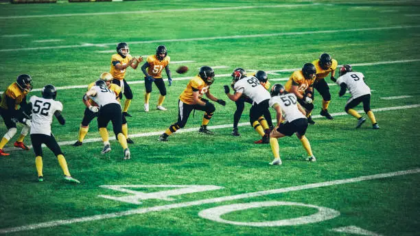 Photo of American Football Teams Start Game: Professional Players, Aggressive Face-off, Tackle, Pass, Fight for Ball and Score. Warrior Competition Full of Brutal Energy, Power, Skill.
