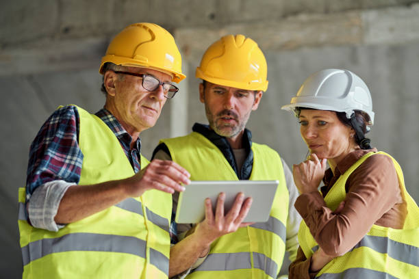 istock Three caucasian engineers discussing over digital tablet on the construction site 1355087244