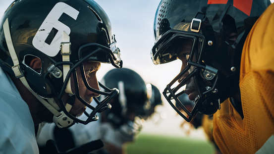 American Football Game Start Teams Ready: Close-up Portrait of Two Professional Players, Aggressive Face-off. Competitive Warriors Full of Brutal Energy, Power, Skill. Dramatic Stare.