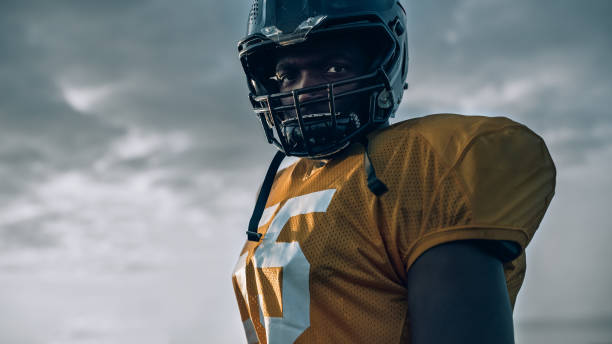 American Football Championship Game: Close-up Portrait of Professional Player Wearing Helmet. Professional Athlete Full of Power, Skill, Determination to Win. Low Angle Shot American Football Championship Game: Close-up Portrait of Professional Player Wearing Helmet. Professional Athlete Full of Power, Skill, Determination to Win. Low Angle Shot rivalry photos stock pictures, royalty-free photos & images