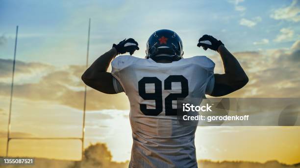 American Football Championship Game Powerful Player Wearing Helmet Flexing His Muscles Dramatically Professional Athlete Determined To Win Cheerful Sportsman Celebrating Back View Shot Stock Photo - Download Image Now