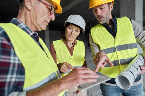 istock Three caucasian engineers discussing over digital tablet on the construction site 1355088836