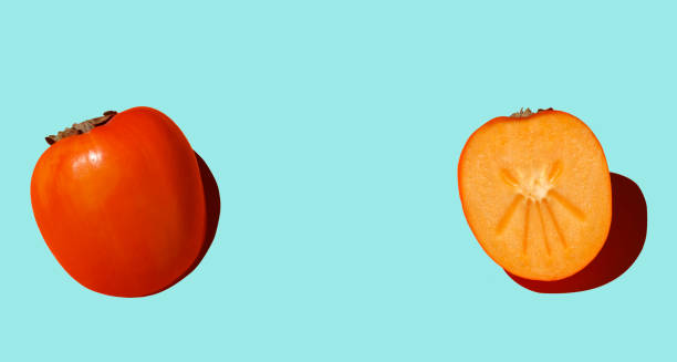 istock Cutaway persimmon on an blue background with hard shadows. 1355089415