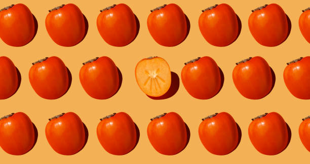 istock Autumn pattern is made with half a persimmon on a beige background. 1355089448