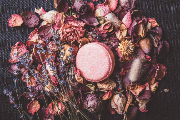 istock Pink color solid shampoo, conditioner bar on various dried multi color flower petals, rose, lavender. Romantic vintage matte style beauty set indoors. 1355090780