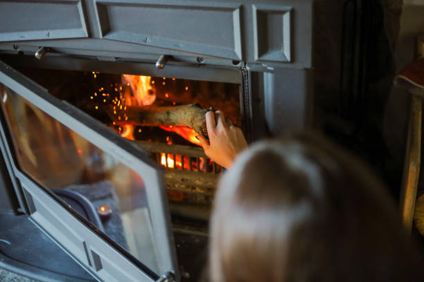 Caucasian woman, putting a tree in her fireplace, to make her Christmas morning cozy stock photo
