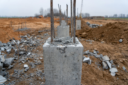 Photo of construction metal rods in concrete pillars against the background of a construction site on the street.