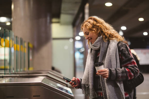 Young woman checking out at metro station using mobile phone
