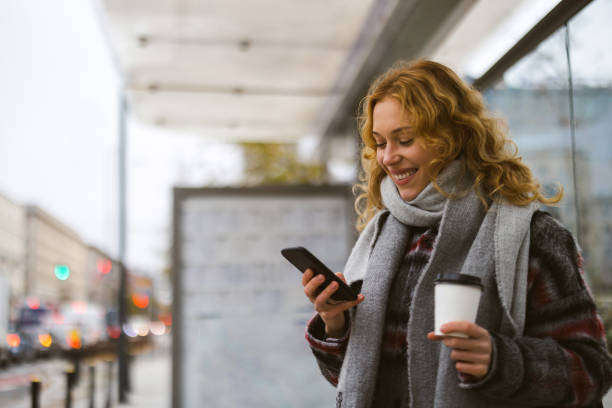Young woman using smart phone at bus station